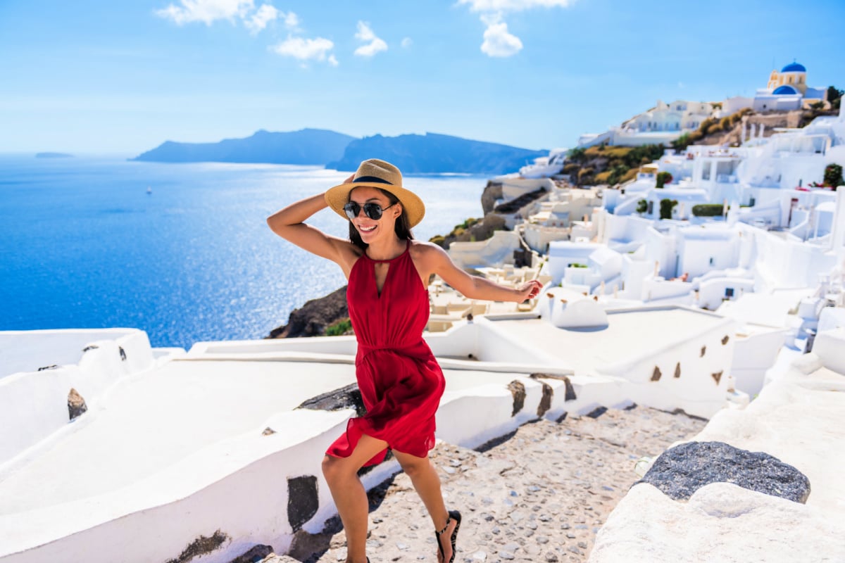 Travel Tourist Happy Woman Running Stairs Santorini, Greek Islands, Greece, Europe. Girl on summer vacation visiting famous tourist destination having fun smiling in Oia